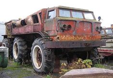 an old rusted out truck sitting on top of a pile of junk next to a dumpster