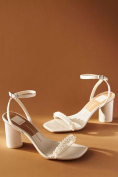 a pair of women's shoes with pearls on the heel and ankle strap, against a brown background