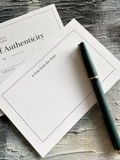 two envelopes sitting on top of each other next to a pen and ink roller