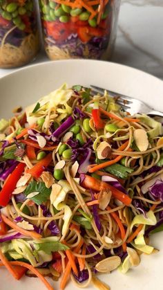 a white plate topped with veggie salad next to two glass jars filled with nuts