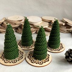 four small pine trees are on coasters next to some wood slices and other decorations