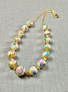 "Murano glass beads with an 'old world' vibe will delight you with genuine 14k gold foil and pastel colors. These artisan created little pieces of art will become one of your favorite jewelry pieces in your wardrobe. The opaque beads are 10mm with flower murrines and subtle textures! Gold fill chain and lobster claw clasp completes the design. The necklace measures 17.5 inches. A wonderful gift for any occasion and arrives in a gift box. ✨ Authentic Murano Glass: Each necklace showcases the unpa Hand Painted Beaded Necklaces With Round Beads For Gift, Multicolor Hand Painted Round Bead Jewelry, Hand Painted Round Bead Necklaces For Gifts, Artistic Beaded Gold Jewelry, Artistic Gold Beaded Jewelry, Elegant Hand-painted Gold Necklaces, Elegant Hand Painted Gold Necklaces, Adjustable Gold Murano Glass Necklaces, Gold Czech Glass Single Strand Jewelry