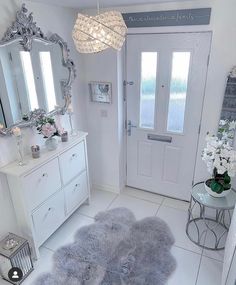 a white bathroom with two gray rugs on the floor and a chandelier