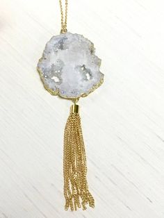 Fall in love with this White Irregular Druzy Necklace with Gold Tassel!  This gorgeous white druzy stone with a 3 inch gold chain link tassel sits on an 18.5 inch gold chain with a lobster claw closure.  It's the perfect compliment to any outfit. Get ready for the compliments!Please note: Due to the one-of-a-kind nature of the medium, exact patterns of the stone area may vary slightly from the images shown. Gold Tassel Dangle Necklace Gift, Lariat Tassel Necklace With Adjustable Chain As Gift, Adjustable Lariat Tassel Necklace As A Gift, White Long Tassel Necklace As Gift, Handmade White Tassel Necklace As Gift, Handmade White Tassel Necklace For Gift, Adjustable White Tassel Necklace Gift, Cowboy Hat Bands, Tassel Necklace Boho