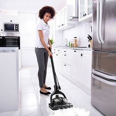 a woman is cleaning the floor with a vacuum