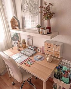 a desk with many items on it in front of a window and some bookshelves