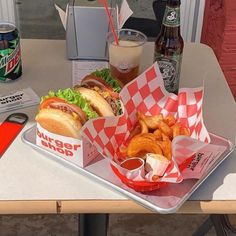 there is a tray that has some food on it and two sodas next to it