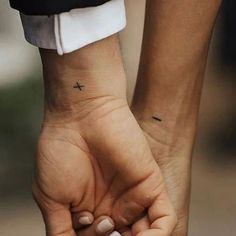 two people holding hands with small tattoos on them