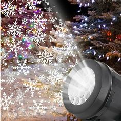 an outdoor light with snowflakes on the ground in front of trees and lights