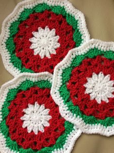 three crocheted coasters with red, green and white snowflakes on them