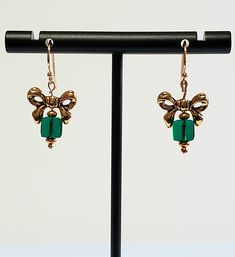 "- Adorable Christmas Presents Hook Earrings with Antique Gold Bow on top. See Photos #1-3. - Swarovski Faceted Crystal 6mm Cubes in Emerald Green creates the \"Gift\". - Gold Plated Roundel Beads accent. - Drop Length 1 1/8\". - 14K Gold Silver Filled Bali Hook Ear Wires with Ball Ends. If you prefer Leverbacks or Angular Hooks with Ball Ends, we can customize for you at no cost. Give us a \"Note\" on Etsy at Checkout. - See same Earring in Red/Gold or Silver in Red or Green, Listed in our Chri Elegant Beaded Earrings As Christmas Gift, Elegant Beaded Earrings For Christmas Gift, Elegant Green Holiday Earrings, Gold Beaded Earrings With Faceted Beads For Gifts, Holiday Gold Beaded Jewelry, Elegant Beaded Jewelry For Holidays, Gold Crystal Earrings With Faceted Beads As Gift, Elegant Christmas Jewelry With Faceted Beads, Bow Earrings