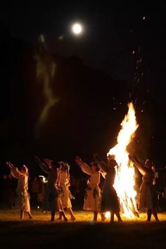 people standing around a fire with their arms in the air