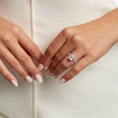 a woman's hands are shown with her wedding ring on her left hand, and the other hand is holding an engagement ring