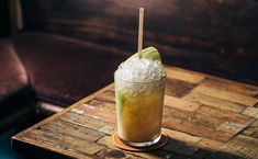 a tall glass filled with ice sitting on top of a wooden table