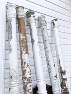 an assortment of different colored and worn wooden posts on the side of a house,