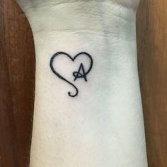 a small heart tattoo on the wrist with an arrow in the shape of a heart