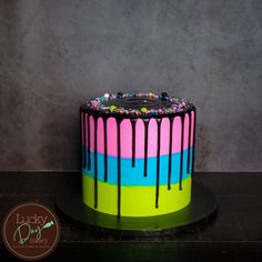 a colorful cake with chocolate drips and sprinkles on the top is sitting on a table