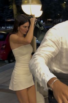 a woman in a white dress walking down the street