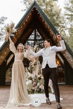 a man and woman standing in front of a wooden structure holding hands with each other