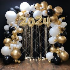 balloons and streamers decorate the entrance to a new year's eve celebration in black, gold and white