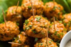 some meatballs with toothpicks on top of them and dipping sauce in a white bowl