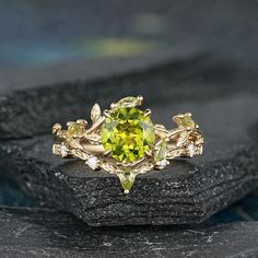 a yellow diamond ring sitting on top of a black stone slab with leaves around it