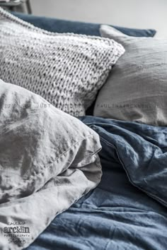 an unmade bed with blue sheets and pillows