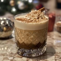 there is a drink with whipped cream and cinnamon on the rim in front of a christmas tree