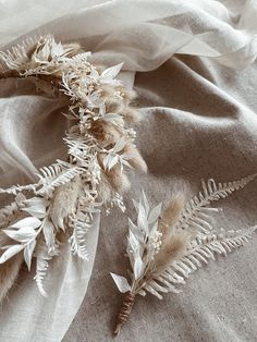 some feathers are laying on top of a cloth covered tablecloth with white and beige colors