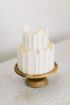 a white cake sitting on top of a wooden platter covered in icing strips