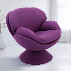 a purple chair sitting on top of a white floor next to a vase filled with flowers