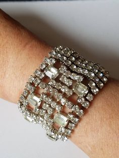 "This Vintage Hollywood Glam Bracelet features ten length of chaton-cut clear rhinestones with 3 vertical columns at the center. The center has six squares with large clear crystals. On one side is a square hinged fold over box clasp. The base metal is plated in Rhodium with exquisite workmanship. This lovely cuff is from Circa; 1950 and is in excellent vintage condition with all rhinestones intact with none missing. Our jeweler has soldiered several squares to keep it from the landfill. If you Arm Candy Bracelets, Bridal Cuff, Candy Bracelet, Hollywood Glam, Wide Cuff, Holiday Jewelry, Rhinestone Bracelet, Vintage Hollywood, Hollywood Glamour