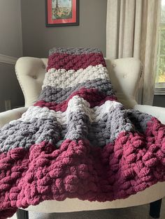 a crocheted blanket sitting on top of a chair in a living room next to a window