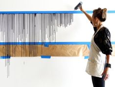 a woman standing in front of a wall hanging on a blue and white striped wall