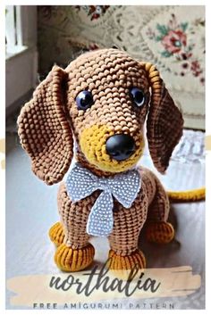 a crocheted dog is sitting on the floor with a bow tie around it's neck