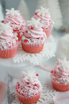 cupcakes with pink frosting and sprinkles on a cake plate