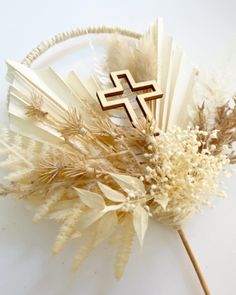 a cross is on top of some dried flowers and sticks in front of a white background