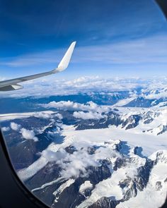 the view out an airplane window shows snow capped mountains