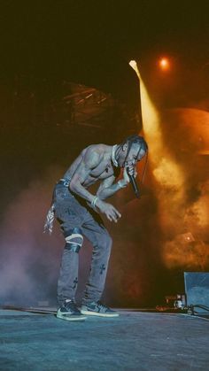 a man standing on top of a stage with his hands in his pockets while holding a microphone