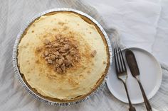 a pie sitting on top of a white plate next to a fork and spoons