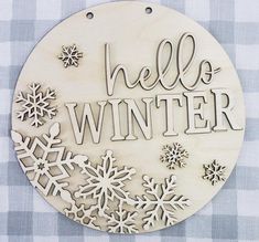 a wooden plaque that says hello winter surrounded by snowflakes