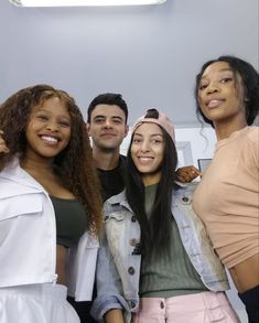 four people posing for the camera in front of a white wall with a light above them