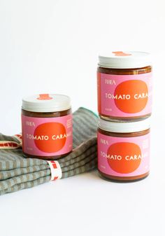 three jars of tomato caramel spread sitting on top of a cloth next to each other