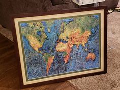 a framed map of the world is on display in front of a couch and coffee table