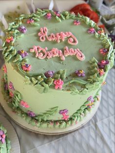 there is a green cake with pink flowers on it and the words happy birthday written in frosting