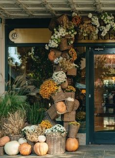 a store front with pumpkins and flowers in baskets on the outside, along with other fall decorations