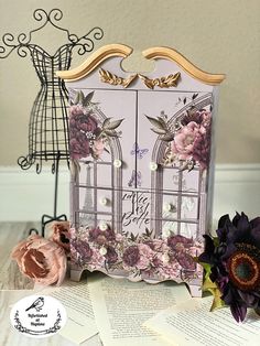 a card with flowers on it next to an open book and some other items in the background