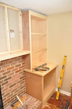 an unfinished room with brick fireplace and shelves