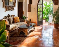 a living room filled with lots of furniture next to a doorway and potted plants