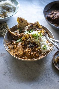 a bowl filled with rice and meat on top of a table next to other dishes